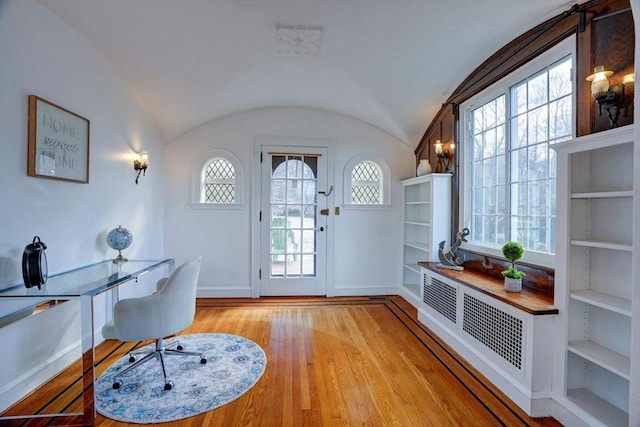 home office featuring a wealth of natural light, lofted ceiling, and light wood-style floors