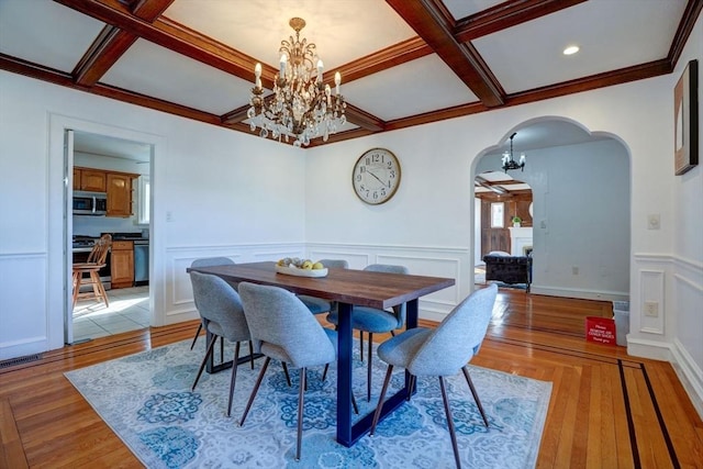 dining room featuring an inviting chandelier, light wood-style flooring, arched walkways, and coffered ceiling