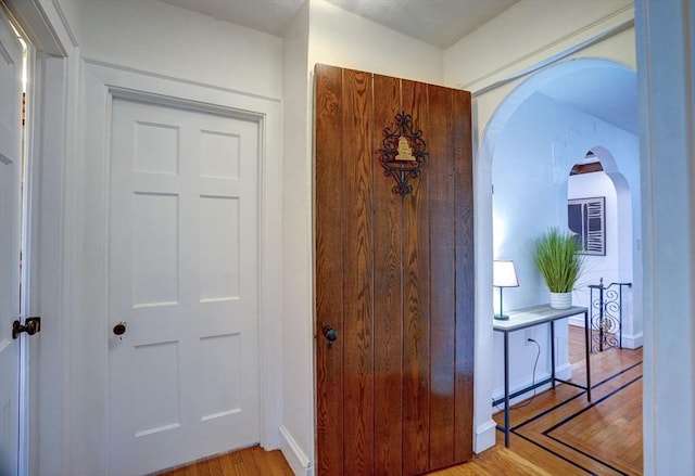 hall featuring arched walkways and light wood-style flooring