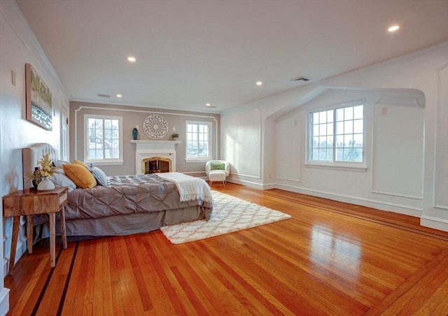 bedroom featuring crown molding, a fireplace, visible vents, and light wood-type flooring