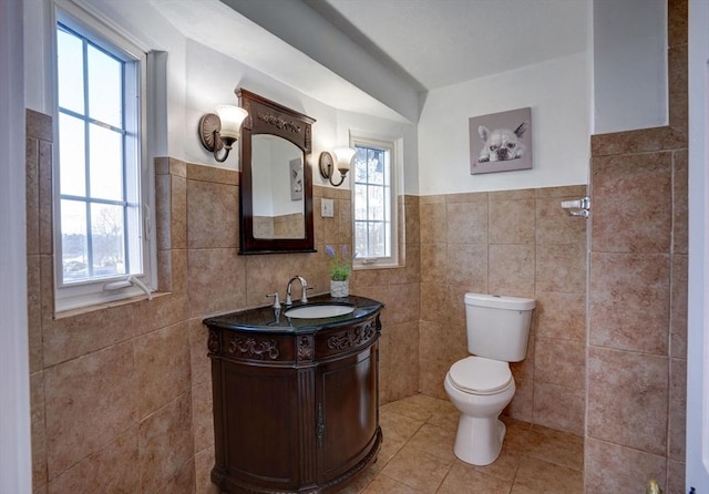 bathroom featuring tile walls, toilet, wainscoting, tile patterned floors, and vanity