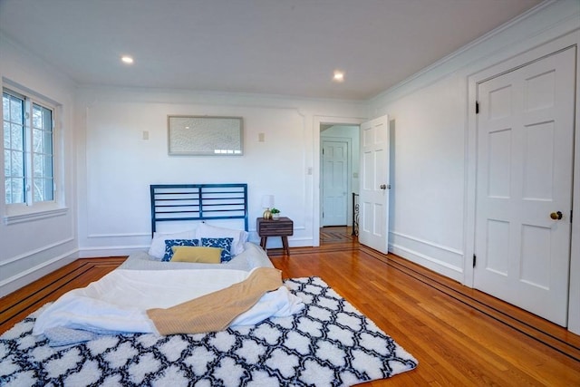 bedroom with recessed lighting, wood finished floors, baseboards, and ornamental molding