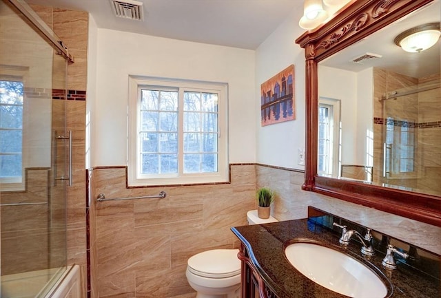 bathroom featuring visible vents, toilet, tile walls, and vanity