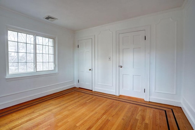 unfurnished bedroom with visible vents, light wood-style floors, and crown molding