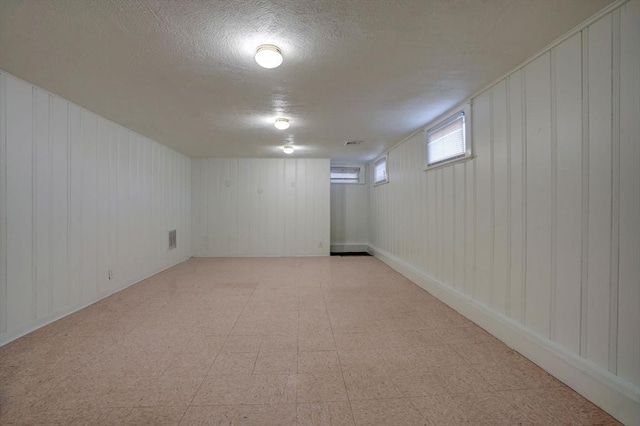 below grade area featuring light floors and a textured ceiling