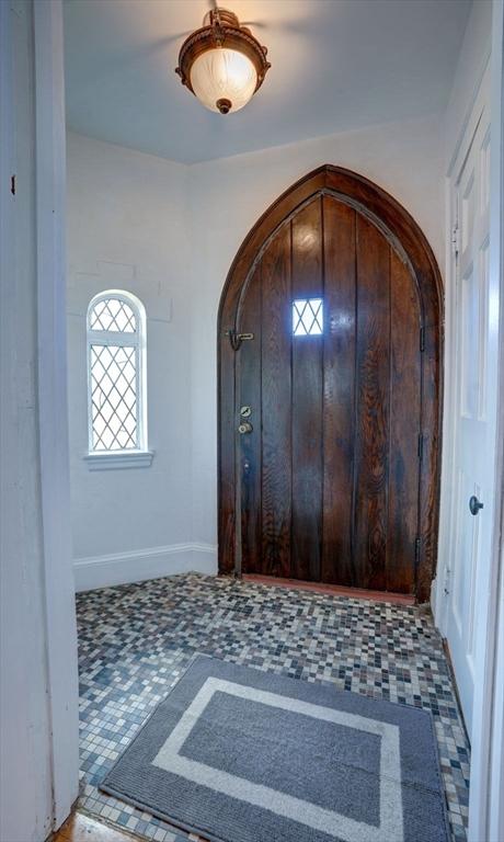 foyer entrance with arched walkways and baseboards