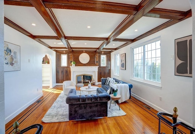 living area featuring wood finished floors, coffered ceiling, a glass covered fireplace, and plenty of natural light