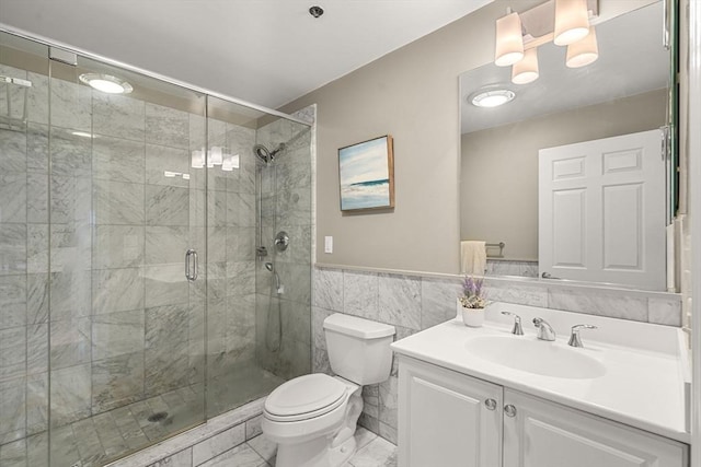 bathroom with vanity, toilet, a shower with door, and tile walls