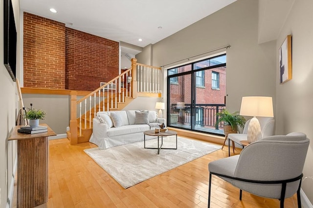 living room featuring a high ceiling, light hardwood / wood-style flooring, and brick wall