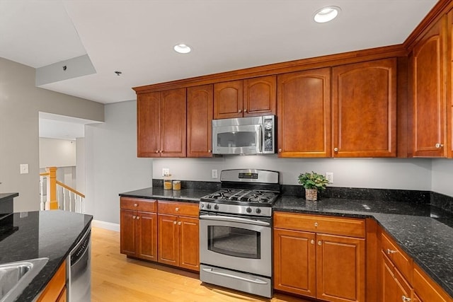 kitchen featuring dark stone countertops, light hardwood / wood-style floors, and appliances with stainless steel finishes