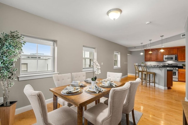 dining space featuring light wood-type flooring and vaulted ceiling