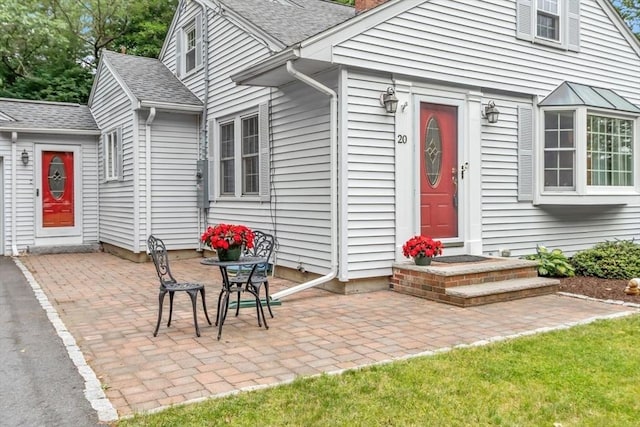 20 Chandler Rd, Andover, MA 01810 - view of exterior entry with a patio, roof with shingles, and a chimney