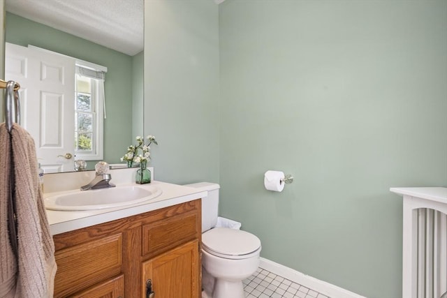 bathroom with tile patterned floors, baseboards, vanity, toilet, and radiator heating unit
