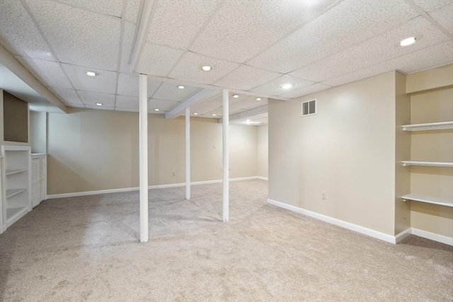 finished below grade area with visible vents, carpet floors, baseboards, a drop ceiling, and recessed lighting