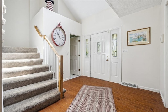 entrance foyer featuring hardwood / wood-style flooring, lofted ceiling, stairs, and visible vents