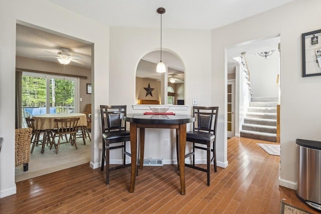 dining space with baseboards, stairs, ceiling fan, and wood finished floors