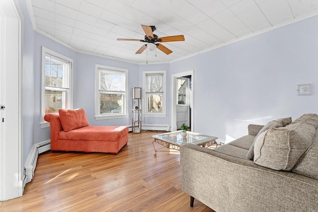 living room with ceiling fan, crown molding, light hardwood / wood-style flooring, and a baseboard heating unit