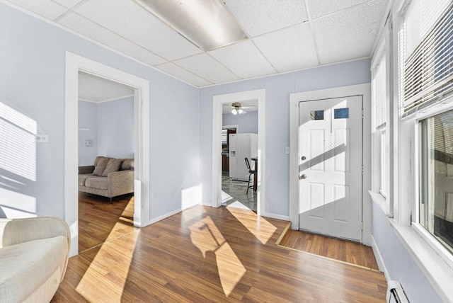 foyer entrance featuring hardwood / wood-style floors, a drop ceiling, a baseboard heating unit, and ceiling fan