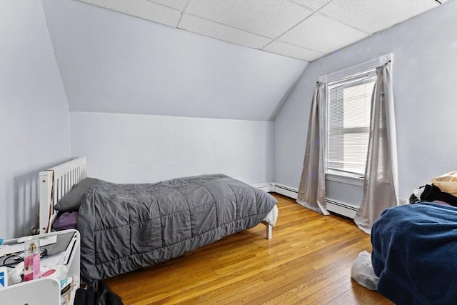 bedroom with a paneled ceiling, light hardwood / wood-style floors, radiator, and vaulted ceiling