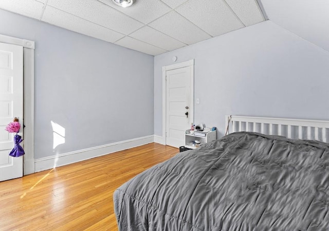 bedroom with a drop ceiling and wood-type flooring