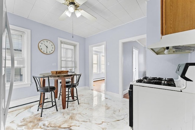 kitchen featuring ceiling fan, a healthy amount of sunlight, white range with gas cooktop, and a baseboard heating unit