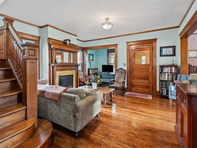 living area with light wood-type flooring, baseboards, a fireplace, and stairs