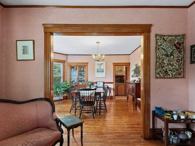 dining room featuring crown molding, light wood-style flooring, and a notable chandelier