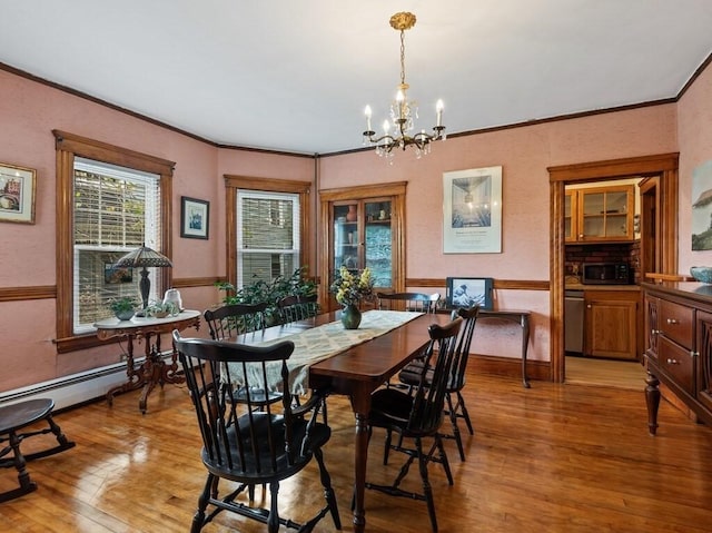 dining space featuring a notable chandelier, light wood-style floors, and ornamental molding