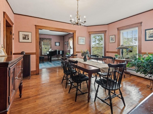 dining room featuring a notable chandelier, light wood-style flooring, and crown molding