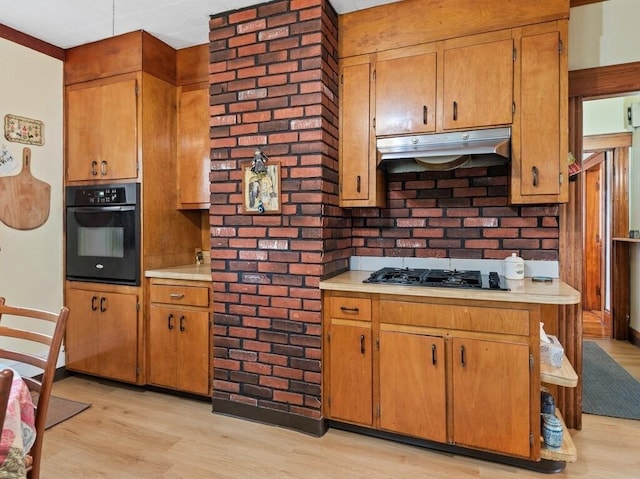 kitchen featuring under cabinet range hood, light wood-style flooring, black appliances, and light countertops