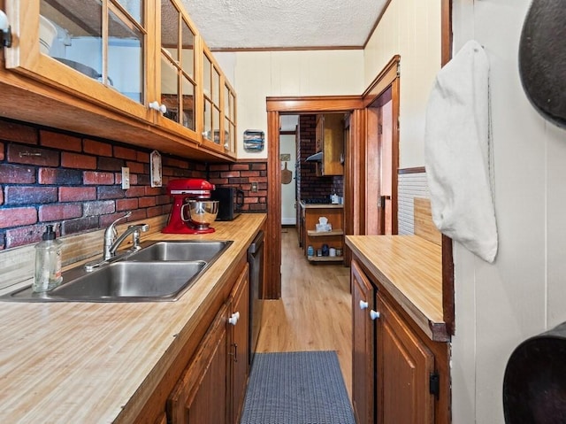 kitchen featuring a sink, glass insert cabinets, a textured ceiling, butcher block counters, and dishwashing machine