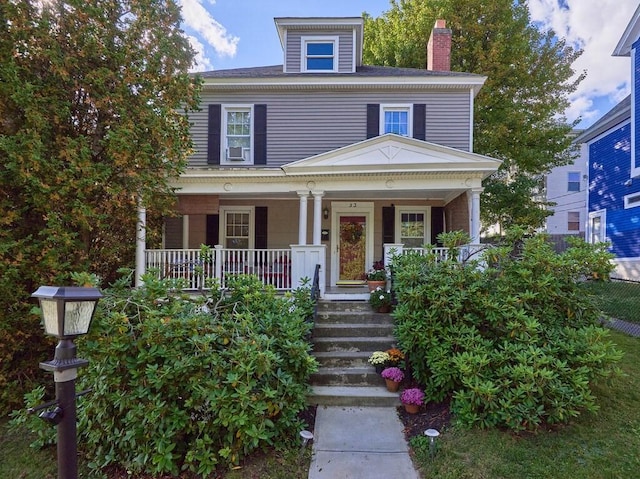 traditional style home featuring covered porch and a chimney