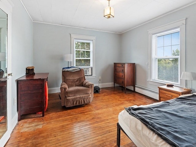 bedroom with crown molding, light wood-style floors, baseboards, and baseboard heating