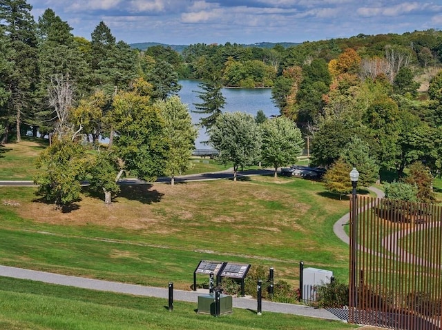 view of property's community with a view of trees, a yard, and a water view