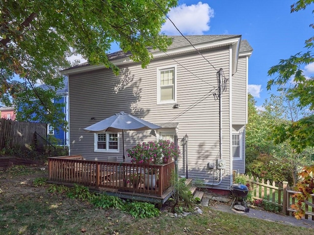 back of property featuring a deck and fence