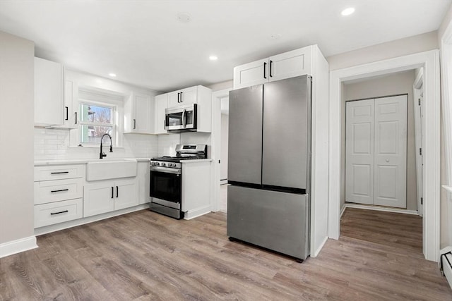 kitchen featuring white cabinetry, stainless steel appliances, sink, and light hardwood / wood-style flooring