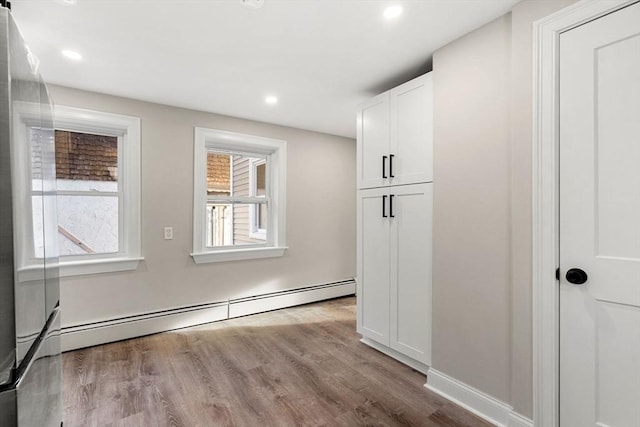 interior space with a baseboard heating unit and light wood-type flooring