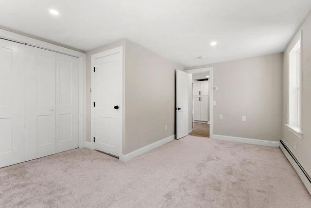 unfurnished bedroom with multiple windows, a baseboard radiator, light colored carpet, and a closet