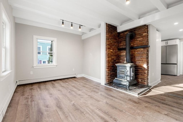 unfurnished living room featuring light hardwood / wood-style flooring, track lighting, a baseboard radiator, beamed ceiling, and a wood stove