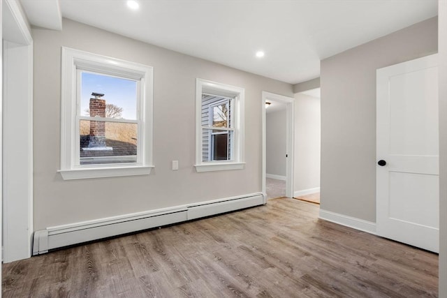 unfurnished room with light hardwood / wood-style flooring and a baseboard heating unit