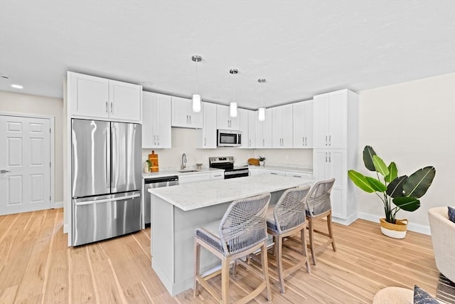 69 Wood St, Hanson, MA 02341 - kitchen featuring stainless steel appliances, a breakfast bar area, white cabinetry, light wood-style floors, and recessed lighting