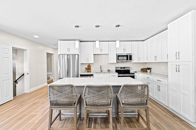 69 Wood St, Hanson, MA 02341 - kitchen with appliances with stainless steel finishes, a breakfast bar, white cabinetry, light wood-style floors, and recessed lighting