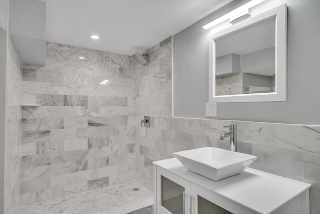 bathroom with a tile shower, tile walls, and vanity