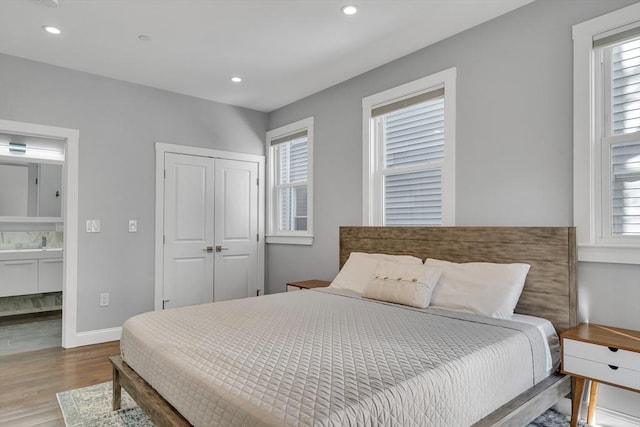 bedroom featuring sink, connected bathroom, light hardwood / wood-style flooring, and a closet