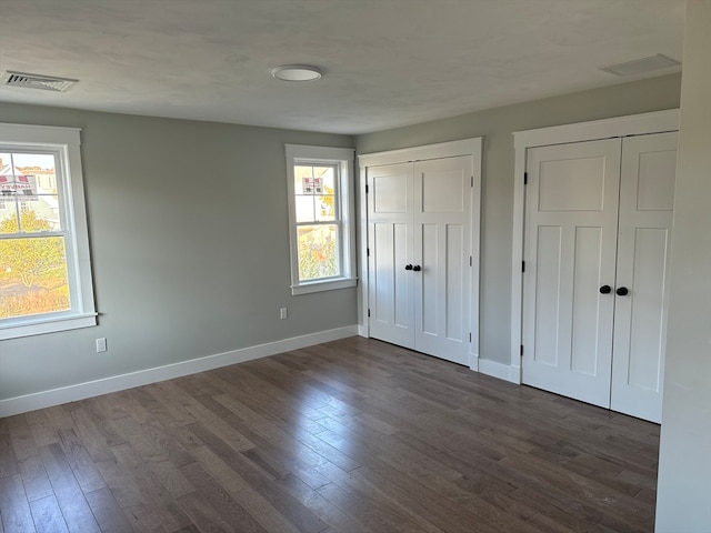 unfurnished bedroom featuring two closets and dark hardwood / wood-style flooring