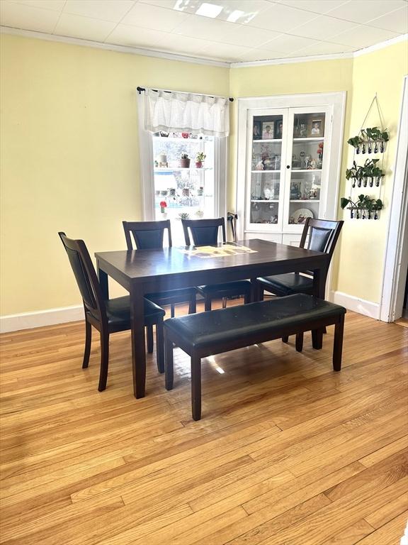 dining space with baseboards, light wood-type flooring, and crown molding