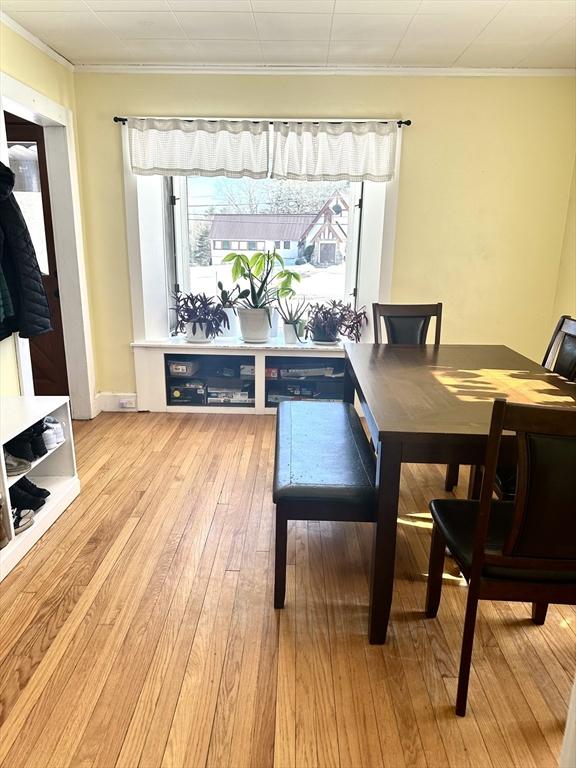 dining area with baseboards, light wood-type flooring, and crown molding