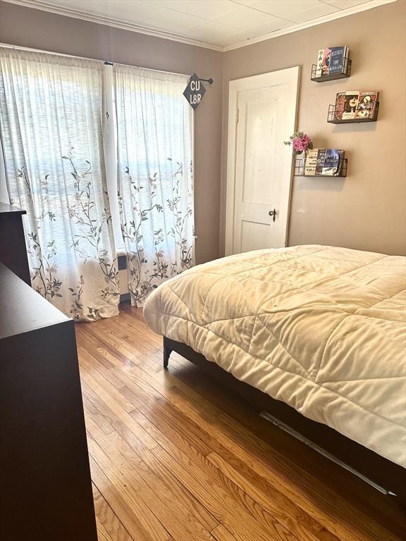 bedroom featuring wood-type flooring and crown molding