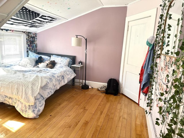 bedroom featuring light wood-type flooring, baseboards, vaulted ceiling, and crown molding