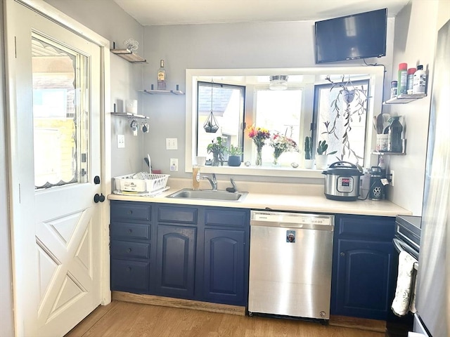 kitchen with a sink, light countertops, blue cabinetry, light wood-type flooring, and dishwasher